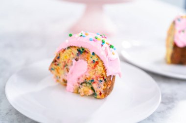 Manzarayı kapat. Dilimlenmiş funfettti demetli kek, üstünde pembe krema ve içinde krema var..