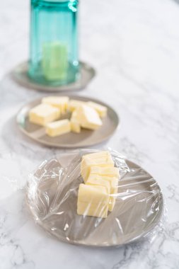 Tezgahın üzerinde yumuşatılmış tuzsuz tereyağı çubukları..