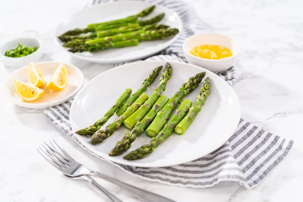 stock image Sering garlic lobster tails with steamed asparagus and lemon wedges on a white plate.