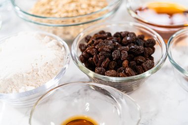 Yumuşak yulaf ezmesi üzümlü cevizli kurabiye pişirmek için cam karışımında ölçülmüş malzemeler..