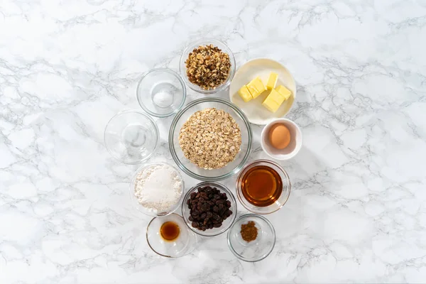 stock image Flat lay. Measured ingredients in glass mixing bowls to bake soft oatmeal raisin walnut cookies.