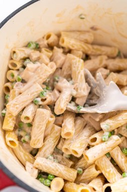 Alfredo soslu tavuk pişirmek için mayalı bir fırının içindekileri karıştırıyorum..