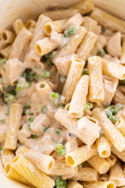 Alfredo soslu tavuk pişirmek için mayalı bir fırının içindekileri karıştırıyorum..