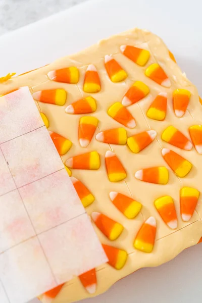 stock image Scoring candy corn fudge using a parchment paper template for cutting into small pieces.