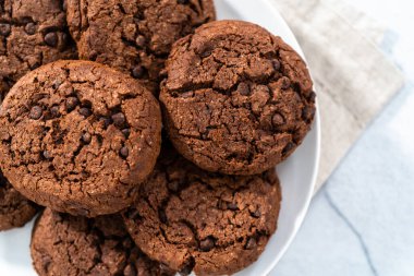 Taze pişmiş çifte çikolatalı kurabiyeler beyaz tabakta..