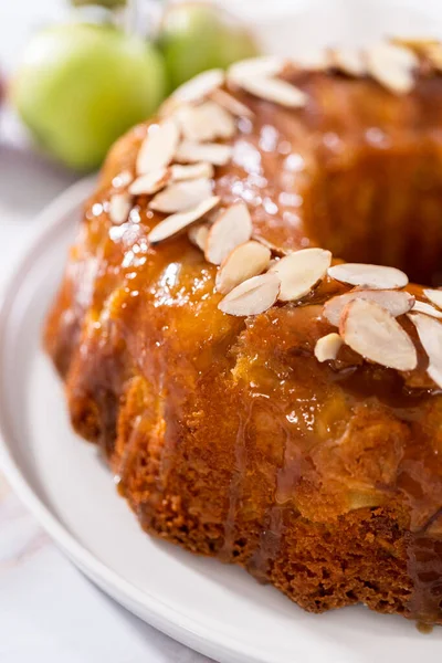 stock image Freshly baked apple bundt cake with caramel glaze on a white plate.