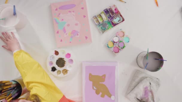 平躺在床上小女孩和妈妈一起在帆布上画丙烯酸颜料 准备做一个远距离学习的艺术项目 — 图库视频影像