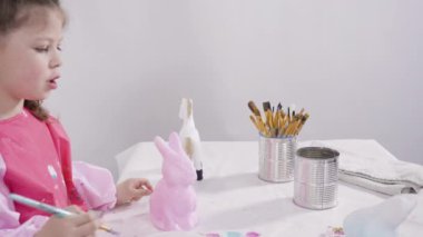 Küçük kız evde eğitim projesi için akrilik boyayla heykelcikler boyuyor..