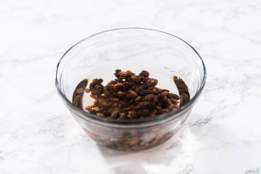 Kurutulmuş kuru üzümleri sıcak suya batırıp mini Paskalya ekmeği pişirmek..