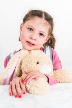 Paskalya yumurtası boyası. Küçük kız doldurulmuş tavşancığına sarılıyor.