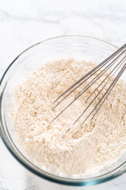 Kuru malzemeleri büyük bir bardakta çırpma kabıyla karıştırıp mini Paskalya ekmeği pişirmek..