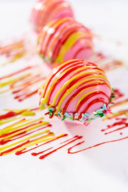 Sıcak çikolata bombalarının üstüne erimiş çikolata serpiştirmek.