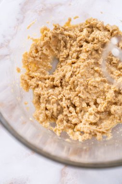 Elmalı yulaflı kurabiye pişirmek için büyük bir bardakta karıştırma malzemesi..