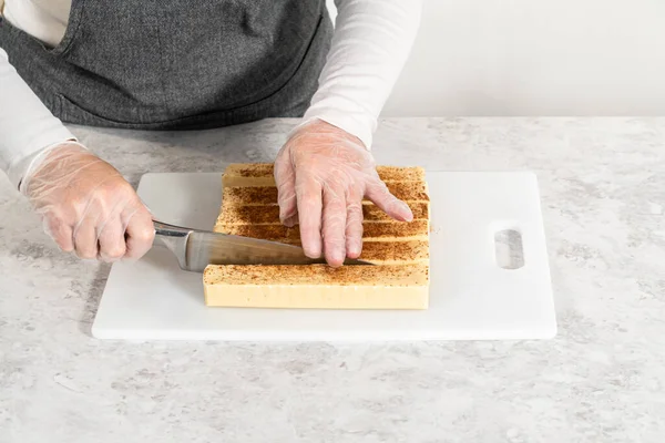 Cutting eggnog fudge into small pieces on a white cutting board.