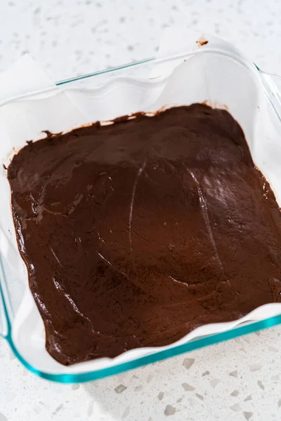 チョコレートピーナッツバター生地を準備する羊皮紙が並ぶベーキングパンに生地の混合物を注ぐ — ストック写真