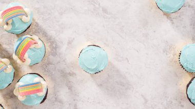 Düz yatıyordu. Adım adım. Çikolatalı kekleri tereyağlı krema ve gökkuşağı şekeriyle süslüyorum..