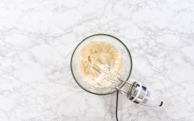 Düz yatıyordu. Krem peynirli krema hazırlamak için büyük bir bardakta karıştırma malzemeleri..