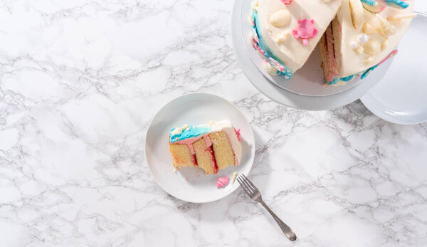 Flat lay. Slice of a mermaid-themed 3 layer vanilla cake with chocolate mermaid tails and seashells on a white plate.
