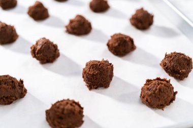 Sevgililer Günü 'nde çikolatalı kurabiye pişirmek için parşömen kağıdıyla kaplı bir yemek tepsisine hamur kepçesiyle kurabiye pişirmek..
