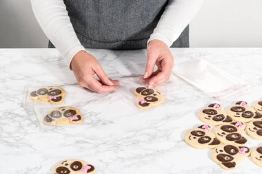 Panda şeklindeki kurabiyeleri paketler, çikolatalı şekerlemeleri tek tek poşetlere doldurur..