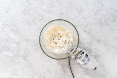 Düz yatıyordu. Havuçlu kek için krem peynirli pasta yapmak için malzemeleri büyük bir karıştırma kabında karıştırıyorum..