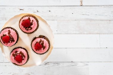 Düz yatıyordu. Çikolatalı ahududu kekleri çikolatalı ganache serpiştirilmiş ve üzeri ahududulu..