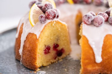 Dilimlenmiş limonlu kek. Şeker kızılcıkları ve limon dilimleri ile süslenmiş..