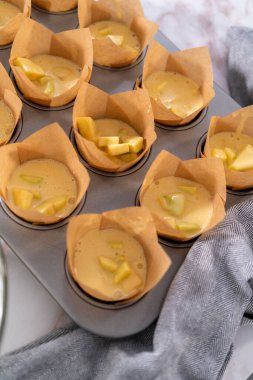 Sharlotka çörekleri pişirmek için parşömen kağıtlarıyla kaplanmış kek tavasına hamur atıyorlar..