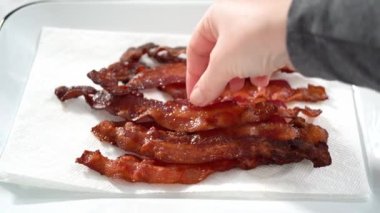 Adım adım. Beyaz tepside pişmiş pastırma şeritleri ve kağıt havlu..