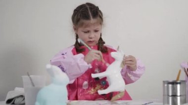 Evde resim dersinde kağıt heykel boyayan küçük bir kız..