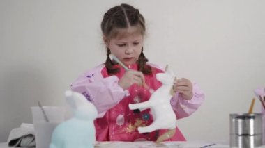Evde resim dersinde kağıt heykel boyayan küçük bir kız..