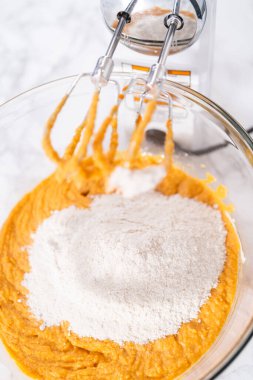 Büyük bir bardakta karıştırılan malzemeler kabaklı kek yapmak için karıştırılıyor..