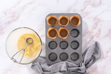 Düz yatıyordu. Sharlotka çörekleri pişirmek için parşömen kağıtlarıyla kaplanmış kek tavasına hamur atıyorlar..