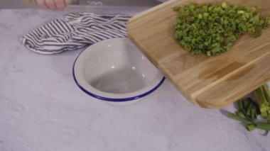 Adım adım. Ağaç kesme tahtasında organik yeşil soğan doğramak.