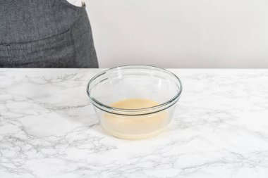 Amerikan bayrağı mini kekleri yapmak için ıslak malzemeleri büyük bir bardakta karıştırıyorum..