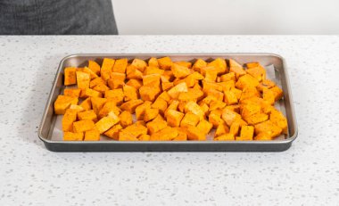 Fırında kızartılmış tatlı patates yapmak için parşömen kağıdıyla kaplı fırında tatlı patatesler..