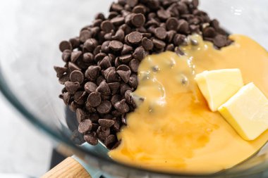 Eriyen beyaz çikolata parçaları ve diğer malzemeler kaynamış suyun üzerine karıştırıp çubuk şekerleme hazırlıyor..