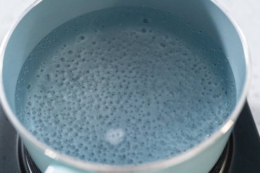 Çikolata parçacıkları ve diğer malzemeleri kaynayan suyun üzerine karıştırıp kabak aromalı şekerleme hazırlıyorum..