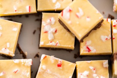 Büyük bir mutfak bıçağıyla şeker kamışı şekerlemesini beyaz bir kesme tahtasında kare parçalara ayırmak..