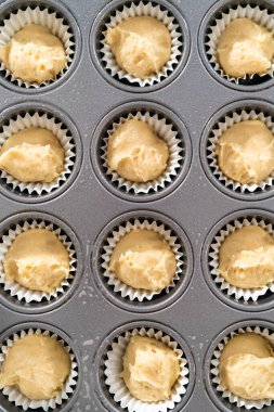 Scooping cupcake batter with dough scoop into a baking pan with liners to bake American flag mini cupcakes.