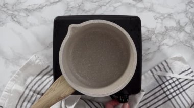 Düz yatıyordu. Küçük bir tencerede çikolatalı ganache hazırlıyorum..