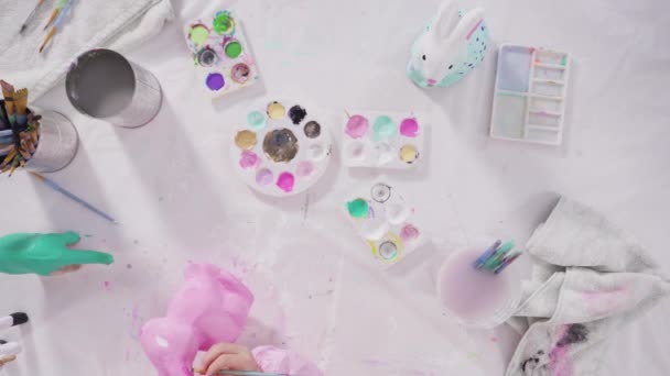 平置きだ 小さな女の子の絵画紙は彼女のホームスクーリングアートプロジェクトのためのアクリル塗料で人形をマッシュ — ストック動画