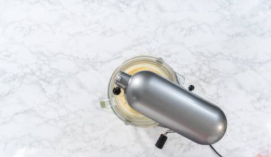 Düz yatıyordu. Beyaz çikolatalı ganache yapmak için mutfak mikserinde beyaz ganache çırpmak..