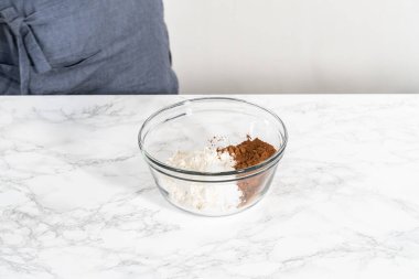 Büyük bir bardakta ıslak malzemeler karıştırarak kırmızı kadife kekler ve beyaz çikolatalı ganache kreması pişiriyorum..