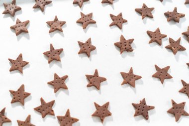 Fırınlanmamış yıldız şekilli çikolatalı krakerler, parşömen kağıdıyla kaplı fırın örtüsü üzerinde..