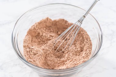 Büyük bir bardakta ıslak malzemeler karıştırarak kırmızı kadife kekler ve beyaz çikolatalı ganache kreması pişiriyorum..