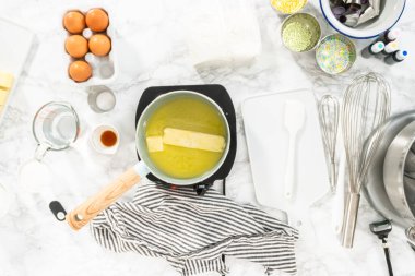 Kek pişirmek için bir tencerede tereyağı çubukları eritiyorum..