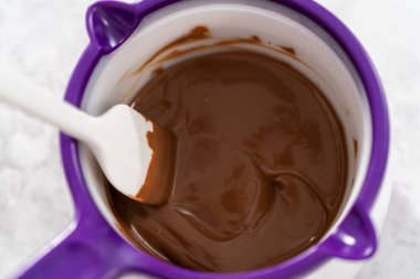 Çikolata erir, şeker tenceresinde erir. Gurme mini çikolatalar hazırlamak için çikolata serpiştirir..