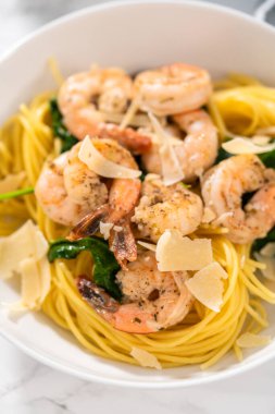 Beyaz seramik kaselerde ıspanaklı sarımsaklı karides makarnası servis ediyorum..