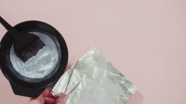Siyah plastik bir kasede pembe arka planda saç boyası tozu..
